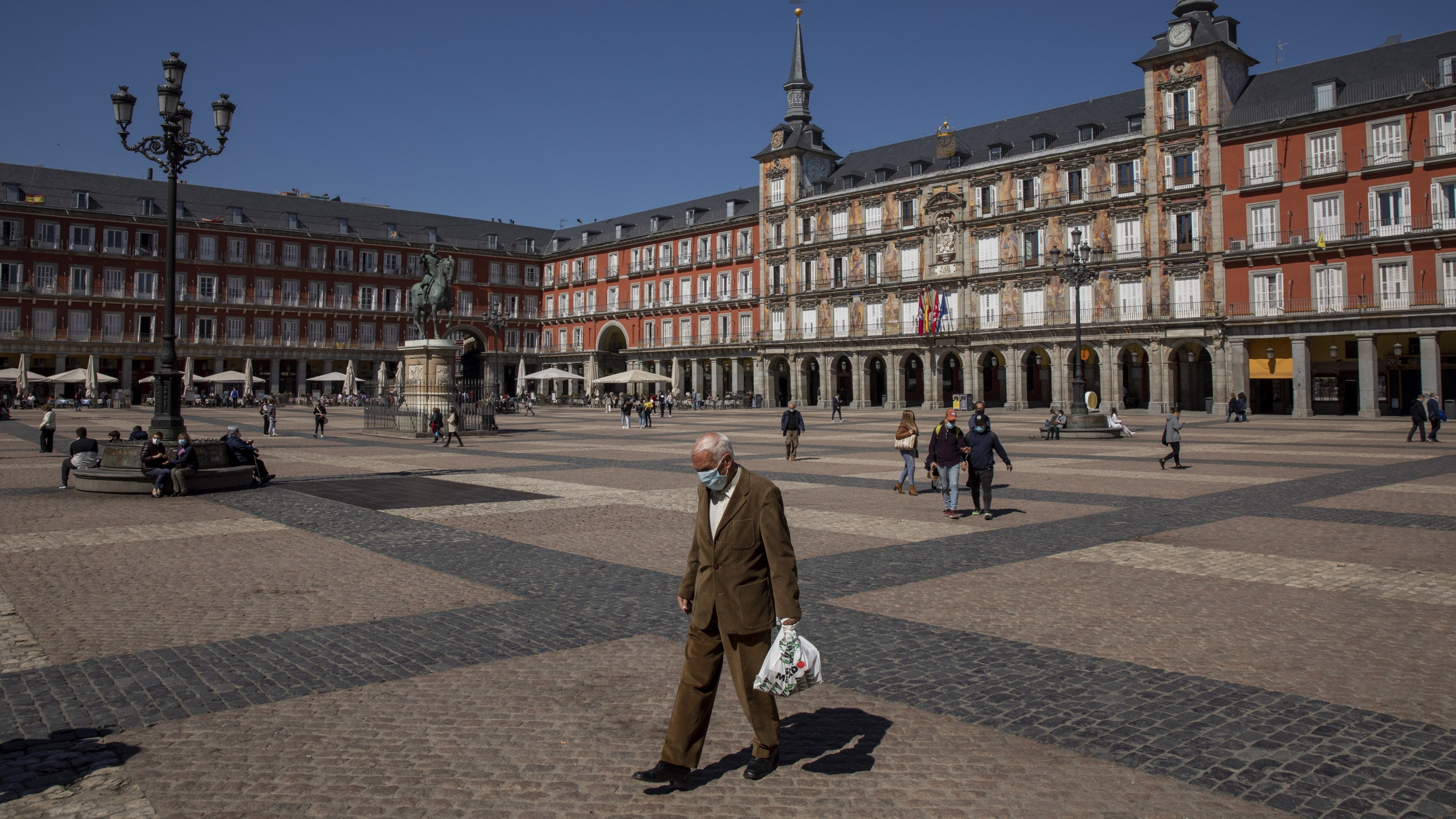 A man walks through Plaza Mayor square in downtown Madrid, Spain, Wednesday, March 24, 2021. A man walks through a plaza during the day