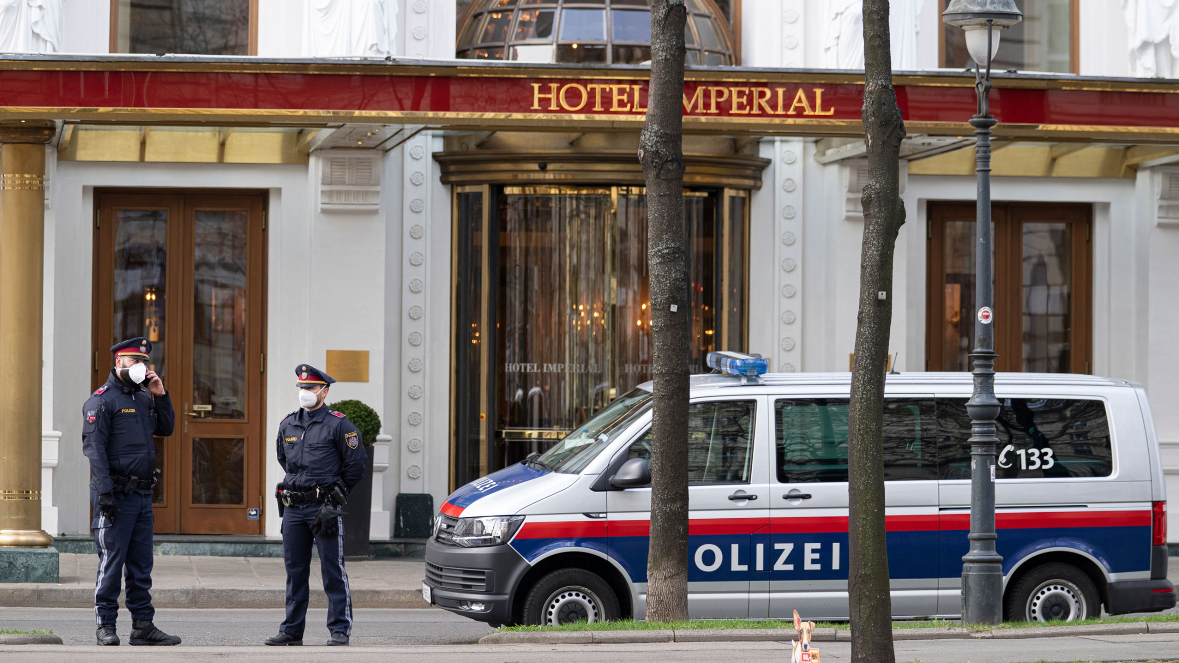 Police officers stand in front of Hotel Imperial where a delegation from Iran is staying in Vienna, Austria, April 6, 2021. Two police officers are shown standing in a street with a police van nearby.