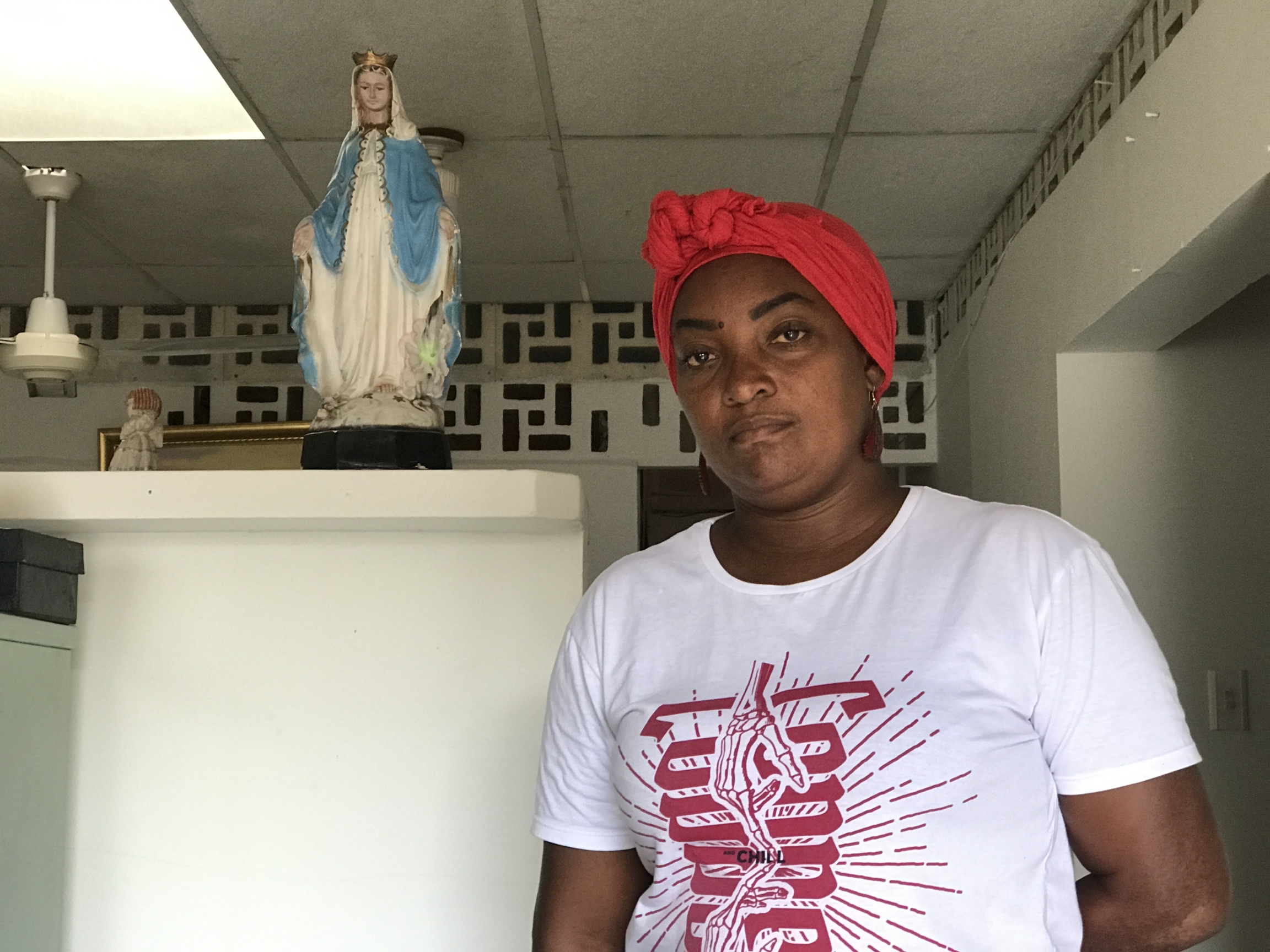 Ana Mosquera, 45, poses for a photo at a local theater group. A woman wearing a red scarf and white and red T-shirt poses for a photo