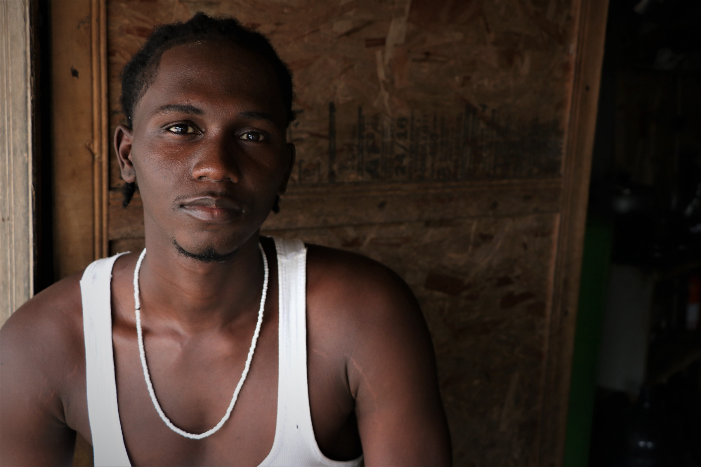 Brayan Ocoro is a resident of the humanitarian space. A young man wearing a white tank poses.
