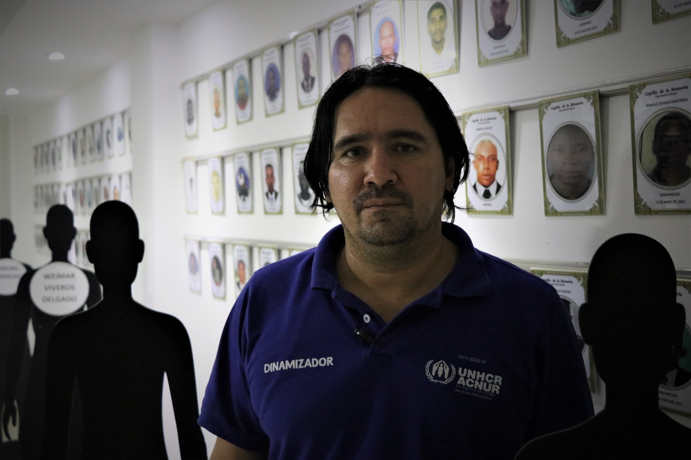 Former priest Adriel Galvan stands at a memorial center for victims of violence. A former priest stands near portraits of victims of violence.