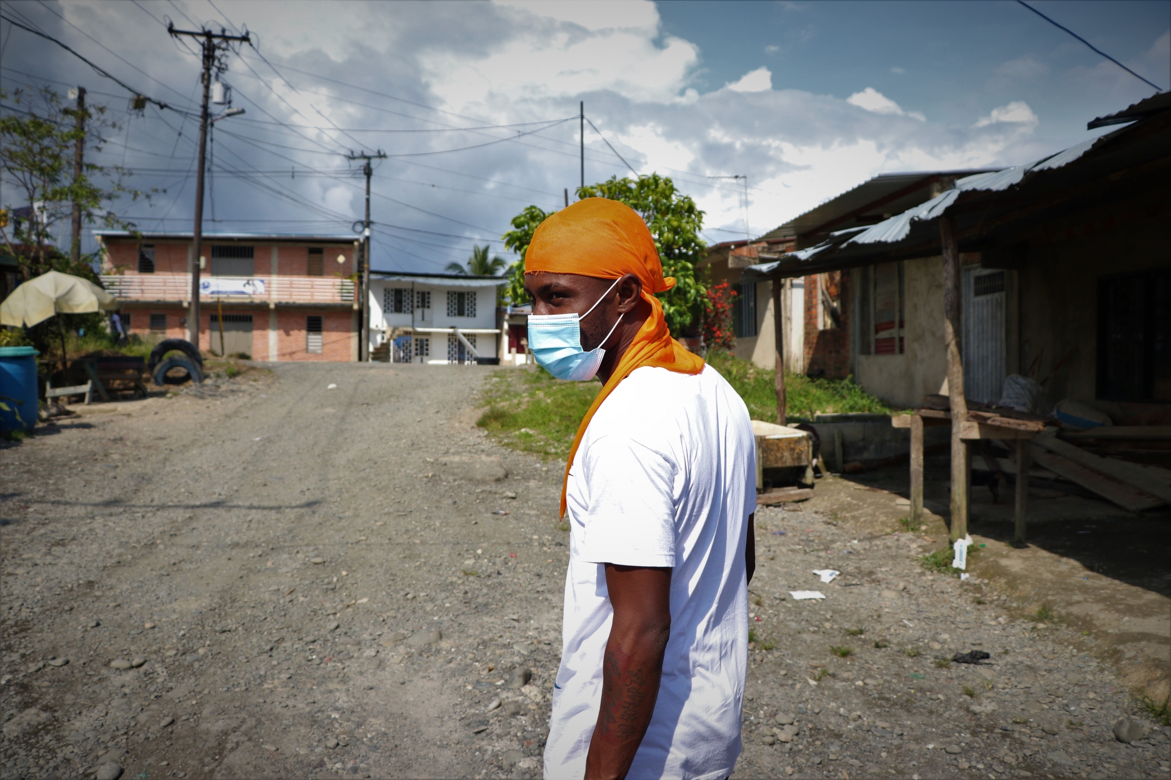 Leonard Renteria, 29, rapper and activist, walks around the neighborhood. A young man walks down a dusty street.