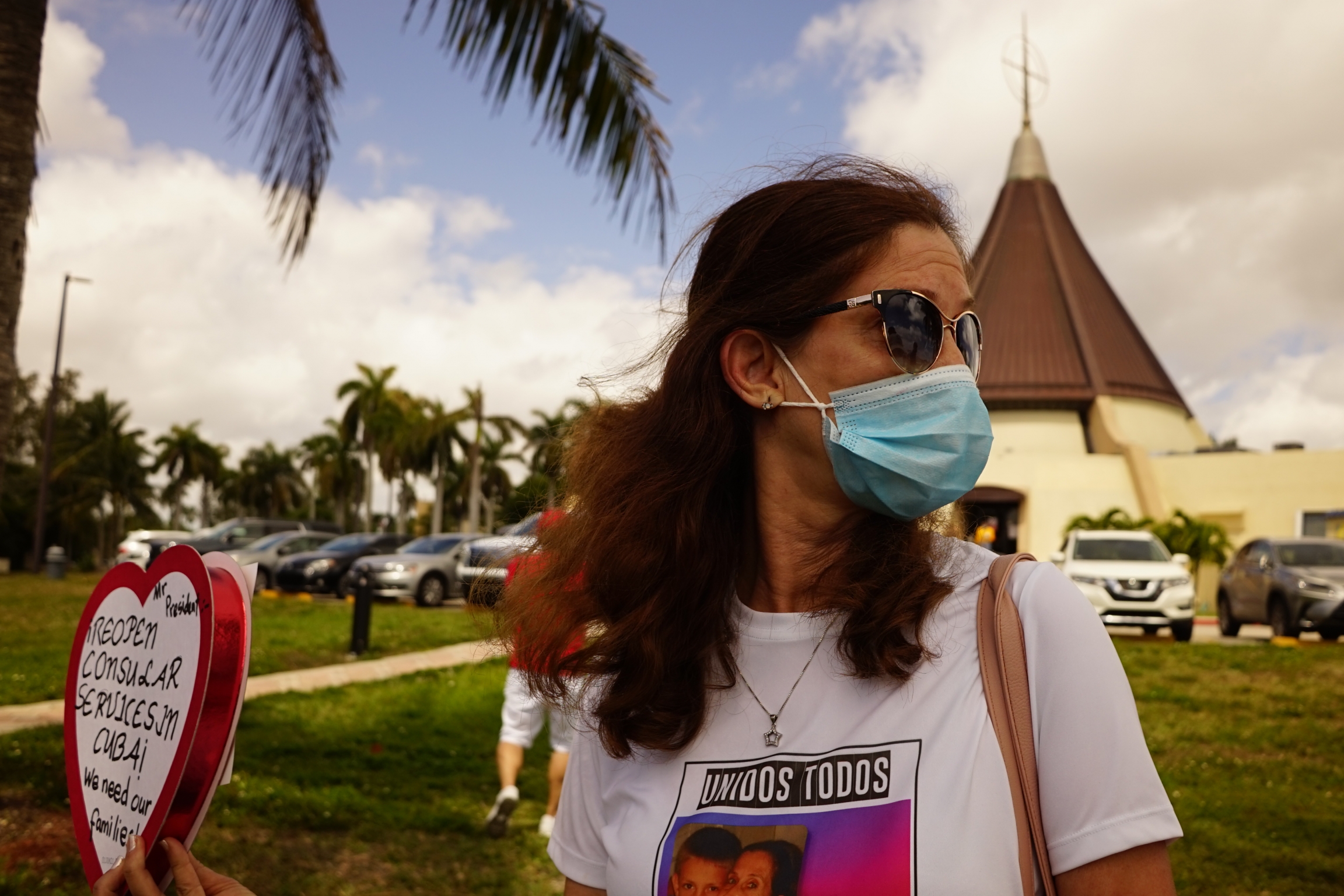 Marietta Medialdea holds a heart-shaped candy box with a message to President Biden to restart consular services in Cuba. Woman holding heart-shaped candy box at a protest.