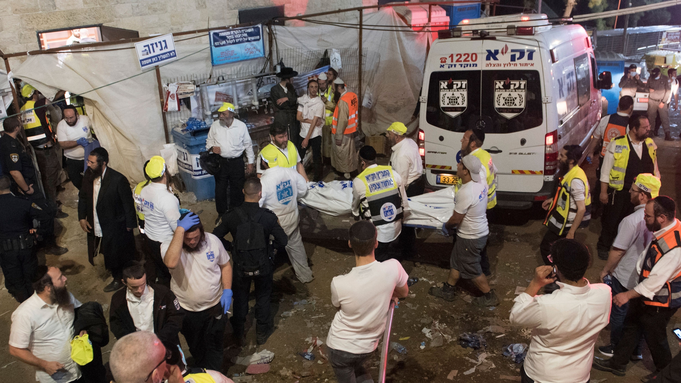 Israeli security officials and rescuers on the scene following a stampede during a Lag Ba'Omer celebrations at Mt. Meron in northern Israel, April 30, 2021. A group of emergency medical professionals are shown with a ambulance in the background.