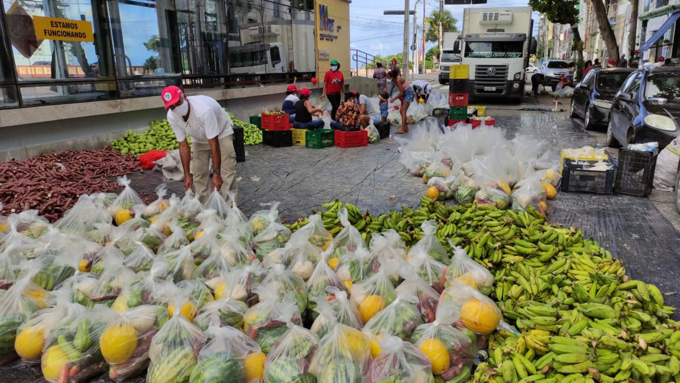 Farmers in the state of Pernambuco deliver 30 tons of produce to a poor community. A man stands near lots of bags of watermelons