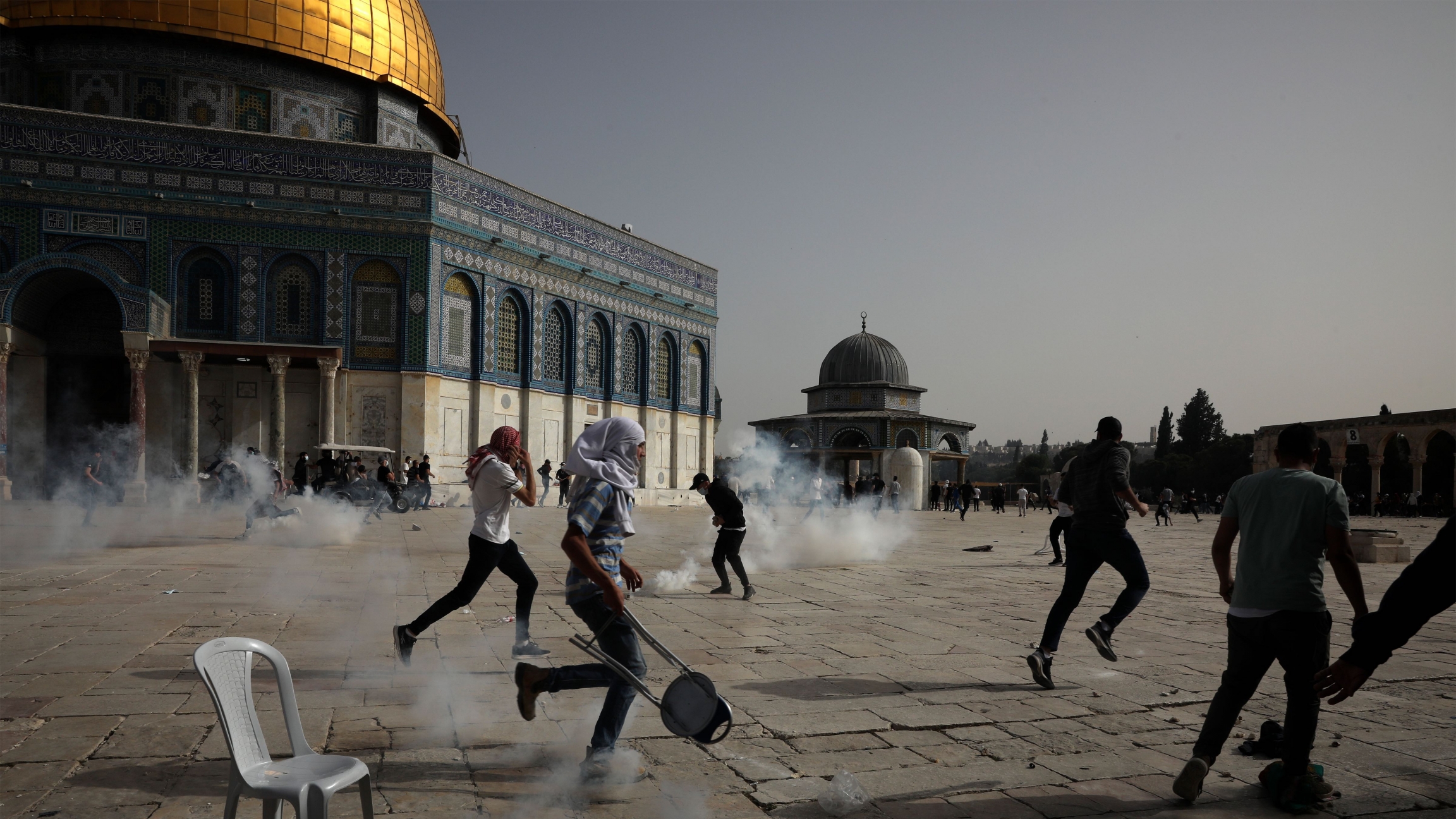 Palestinians run away from tear gas during clashes with Israeli security forces at the Al-Aqsa Mosque compound in Jerusalem's Old City Monday, May 10, 2021. Palestinians run away from tear gas during clashes with Israeli security forces at the Al-Aqsa Mosque compound in Jerusalem's Old City Monday, May 10, 2021.
