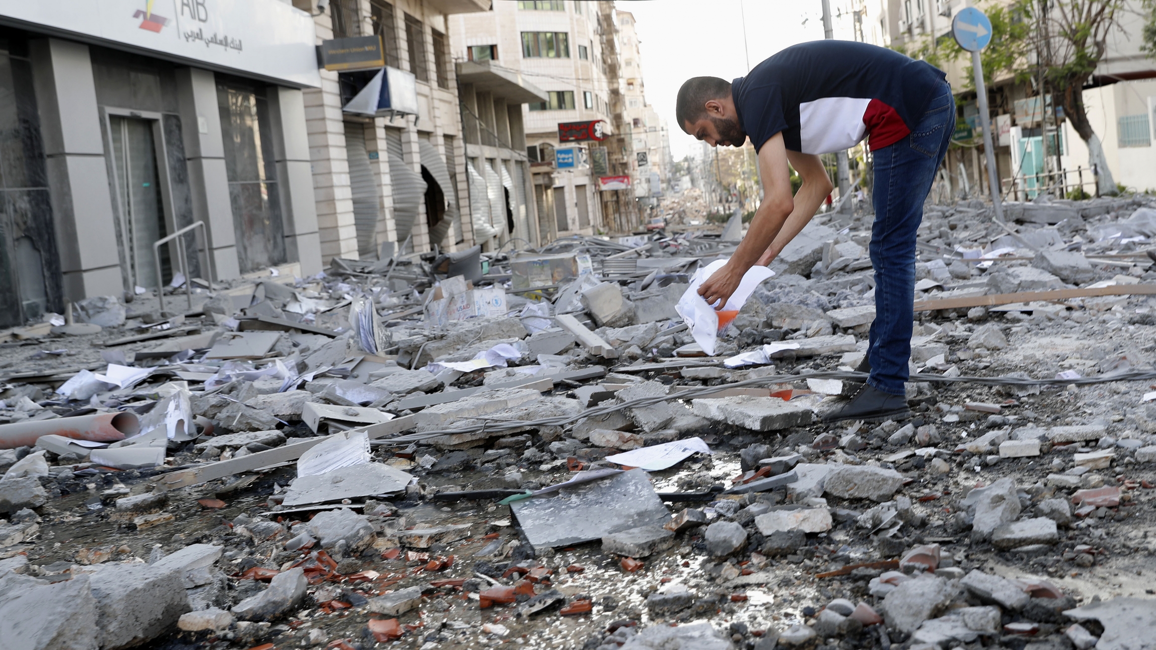 A man inspects the rubble of destroyed commercial building and Gaza health care clinic following an Israeli airstrike on the upper floors of a commercial building near the Health Ministry in Gaza City, on Monday, May 17, 2021. A man looks through the rubble.