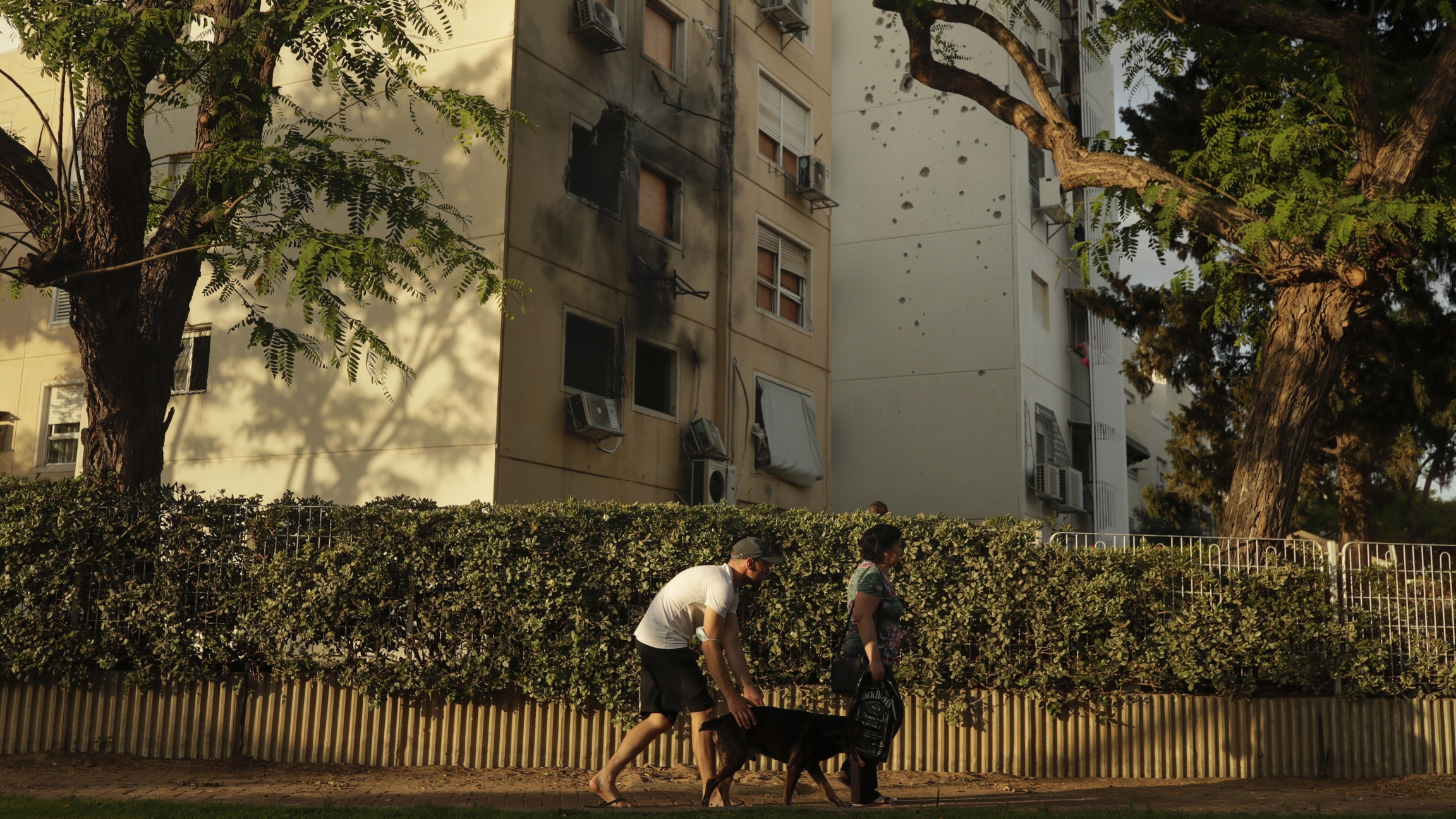 People walk by a damaged residential building after it was hit by a rocket fired from the Gaza Strip last week, in Ashkelon, Israel, Friday, May 21, 2021. People walk by a damaged residential building after it was hit by a rocket fired from the Gaza Strip.