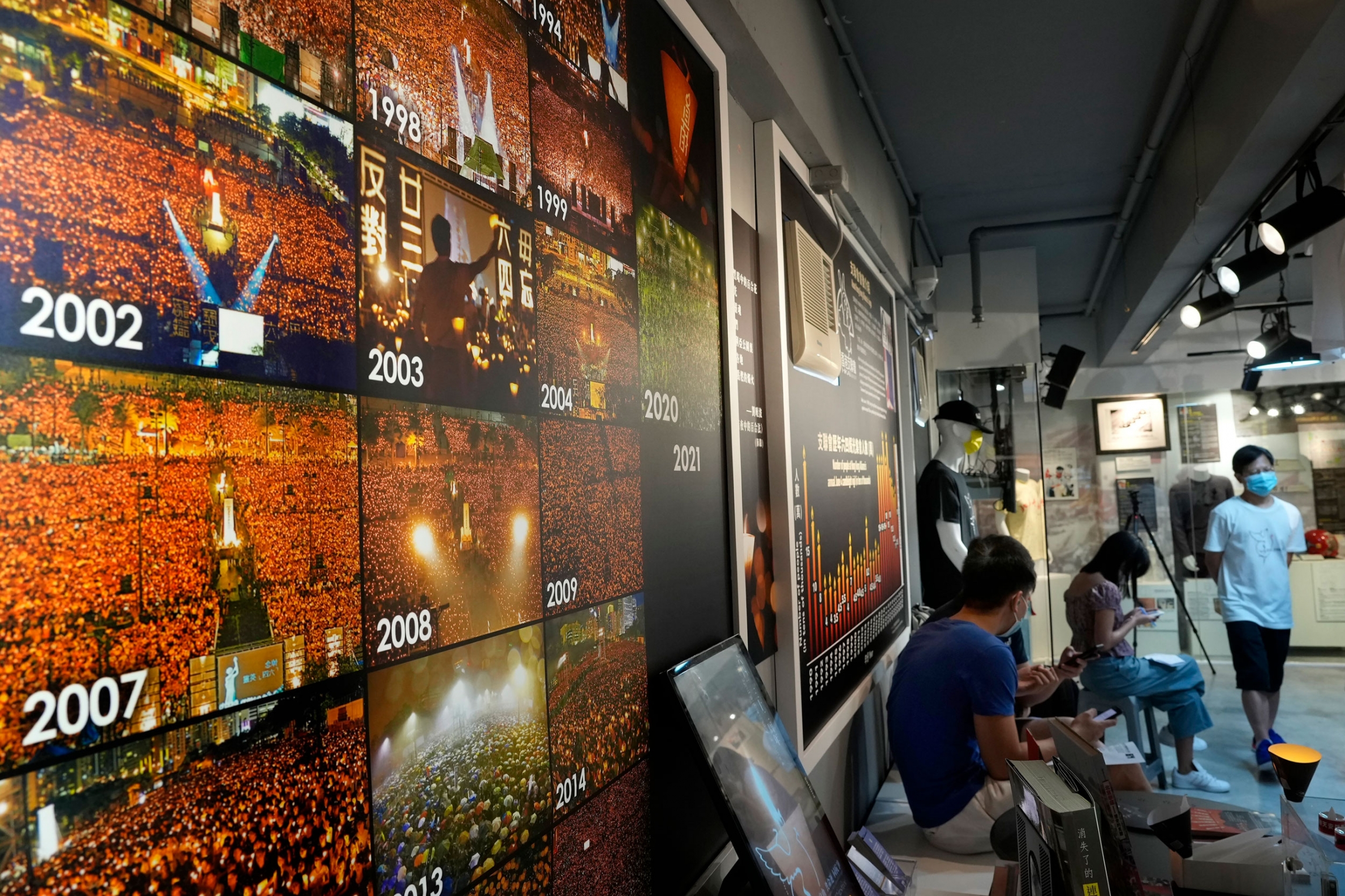 Pictures for past years of people gathered during a candlelight vigil at Victoria Park are displayed at the "June 4 Memorial Museum." A wall of photographs showing hundreds of people gathered and holding up lit candles.
