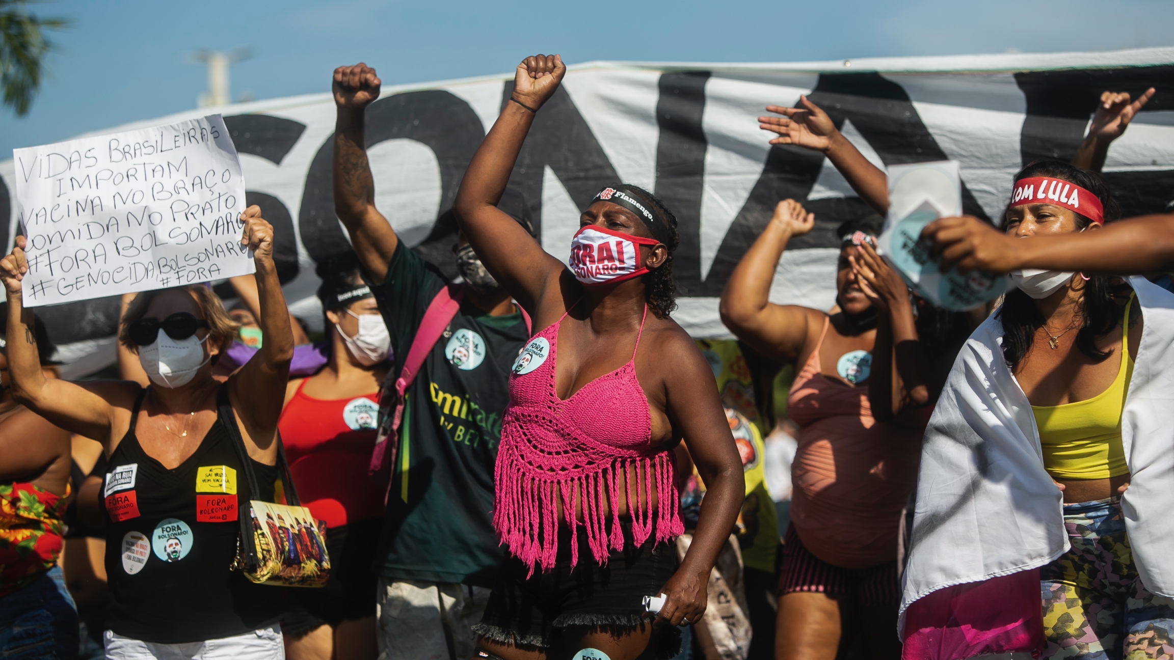 Demonstrators shout slogans during a protest against the government's response in combating COVID-19, demanding the impeachment of President Jair Bolsonaro Demonstrators in front of a banner holding their fists up in the air