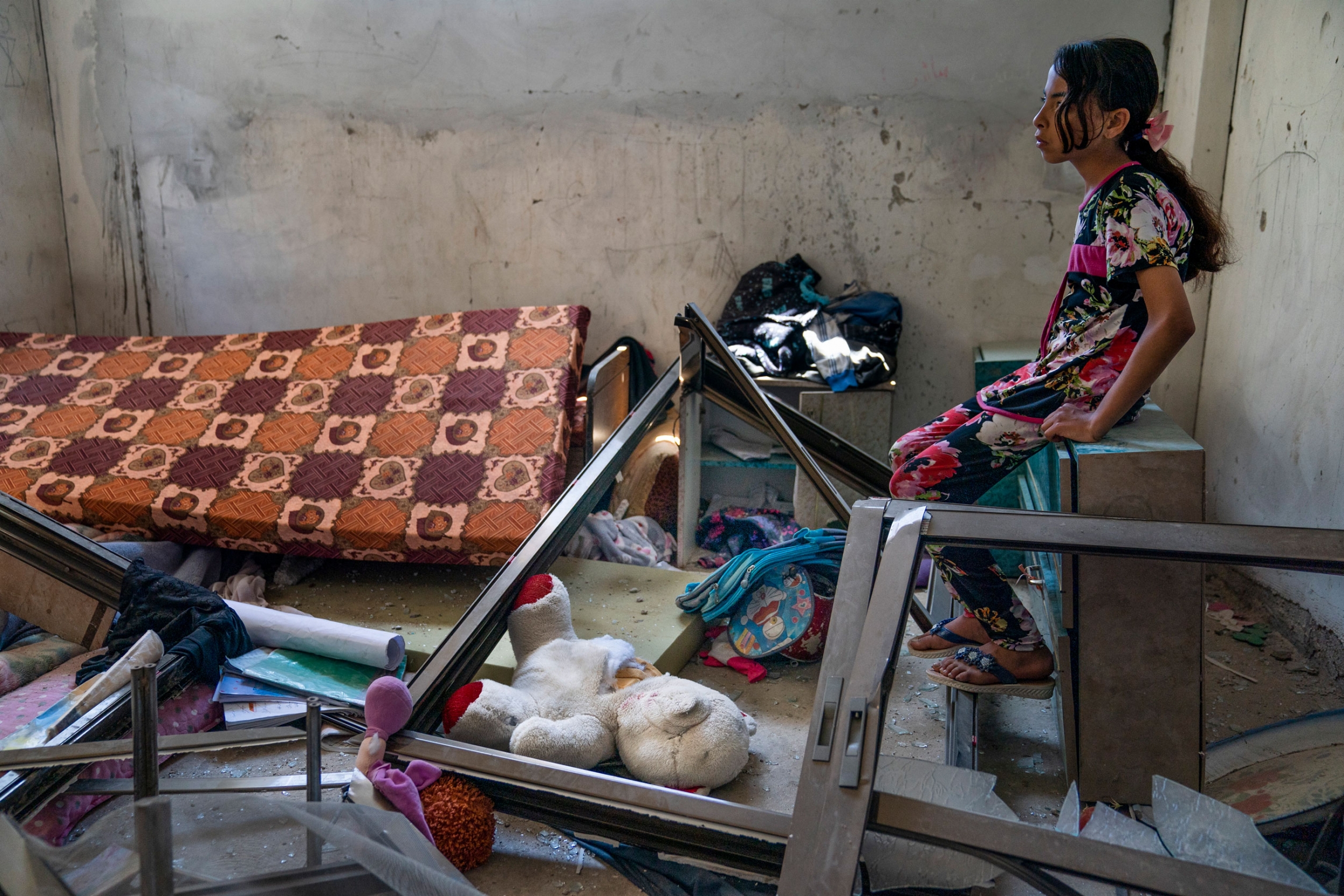 Amal Nassir, 11, sits for a portrait in her war-damaged bedroom in Beit Hanoun, Gaza Strip, May 26, 2021. A young girl sits on a dresser in a room strewn items scattered because of the Israel-Hamas war.