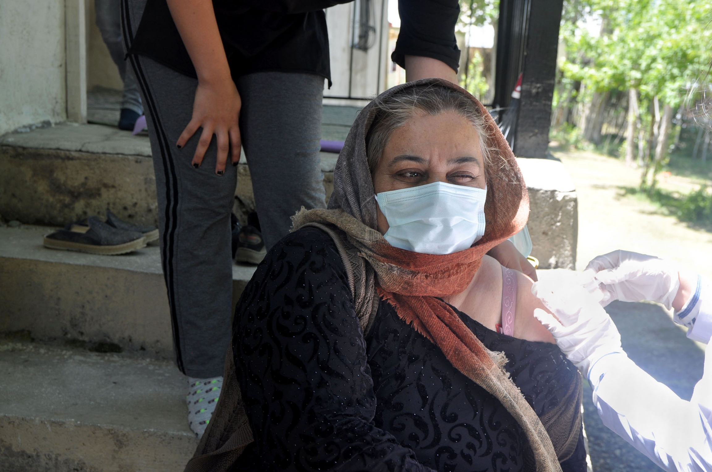 Emine Saruhan winces during a COVID-19 vaccination shot on her front porch in the town of Ömerova. The 46-year-old has a health condition, and hoped a vaccine would alleviate some of her fears. Emine Saruhan winces during a COVID vaccination shot on her front porch in the town of Ömerova. The 46-year-old has a health condition, and hoped a vaccine would alleviate some of her fears.