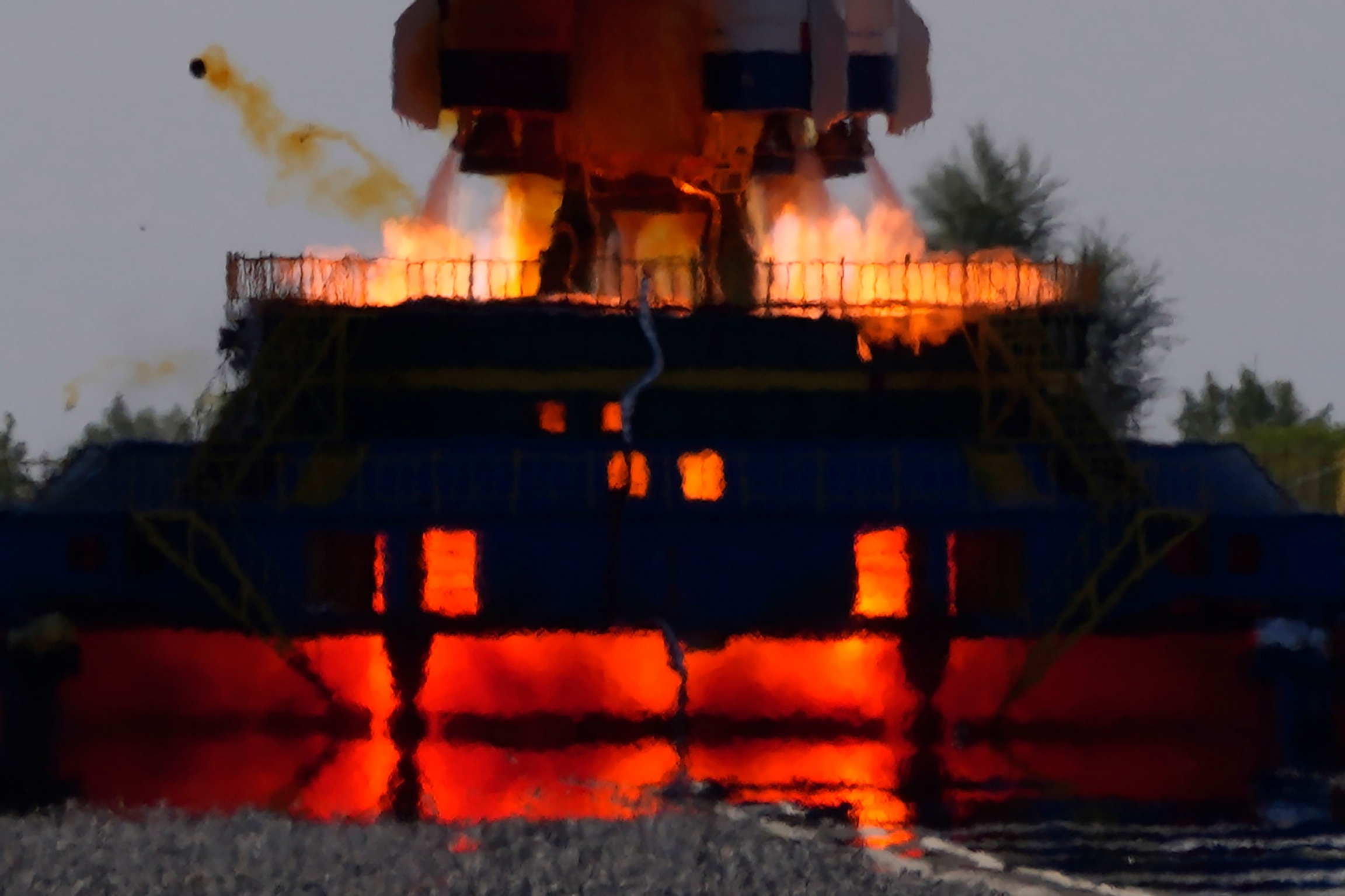 Ignition engulfs the launch pad as a Long March-2F Y12 rocket carrying a crew of Chinese astronauts lifts off. A close up photograph shows fire coming out of the exhaust of the rockets carrying the Chinese spaceship.