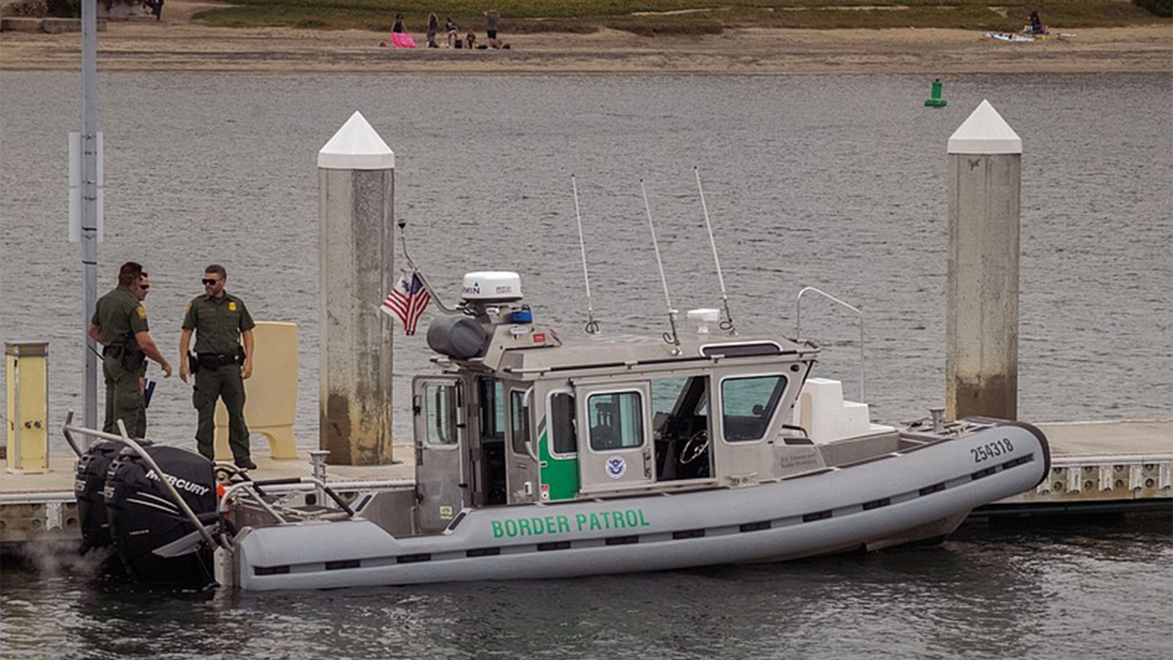 A boat that's now part of the Border Patrol's marine unit, created in response to an increase in smuggling incidents in San Diego, California Three men in green suits stand on a small boat that says "Border Patrol" with an American flag in the middle