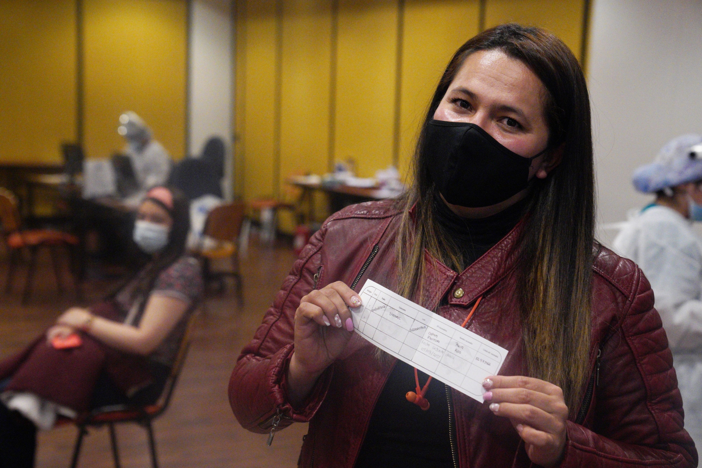A Movistar employee poses with her vaccination certificate on July 4. The phone company signed up for the privately funded vaccination scheme and bought vaccines from more than 1,000 employees. A masked woman holds up her vaccine certificate.