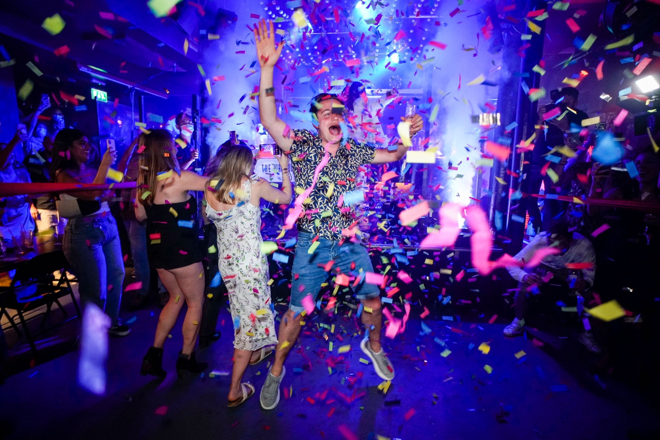 A man jumps on the dance floor shortly after the reopening, at The Piano Works in Farringdon, in London, July 19, 2021. A man is shown jumping in the air amid colorful confetti flying all around.