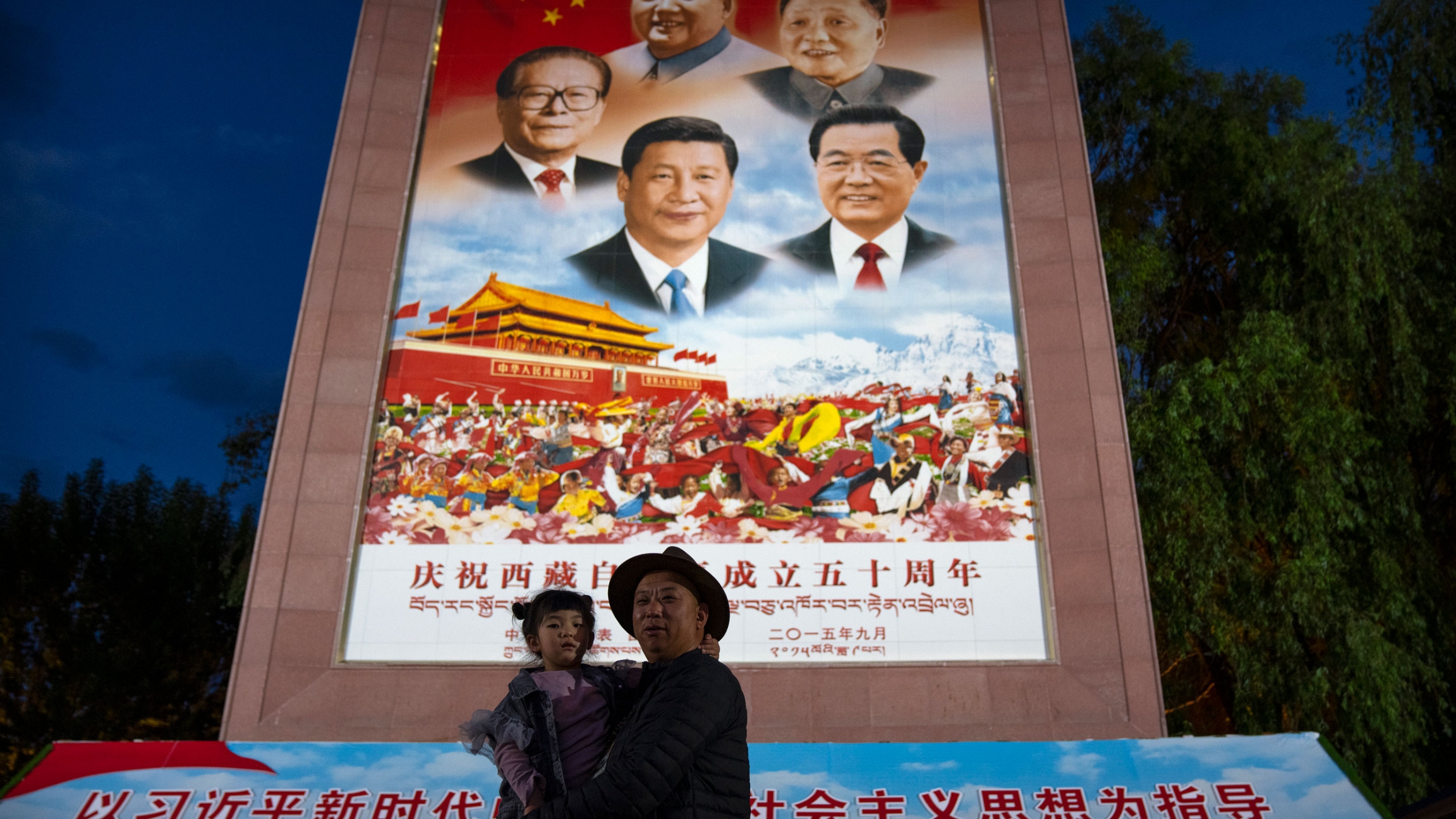 A man holds a girl as they pose for a photo in front of a large mural depicting Chinese President Xi Jinping, bottom center, and other Chinese leaders at a public square at the base of the Potala Palace in Lhasa in western China's Tibet Autonomous Region A man holds a girl as they pose for a photo in front of a large mural depicting Chinese President Xi Jinping, bottom center, and other Chinese leaders at a public square at the base of the Potala Palace in Lhasa in western China's Tibet Autonomous Region