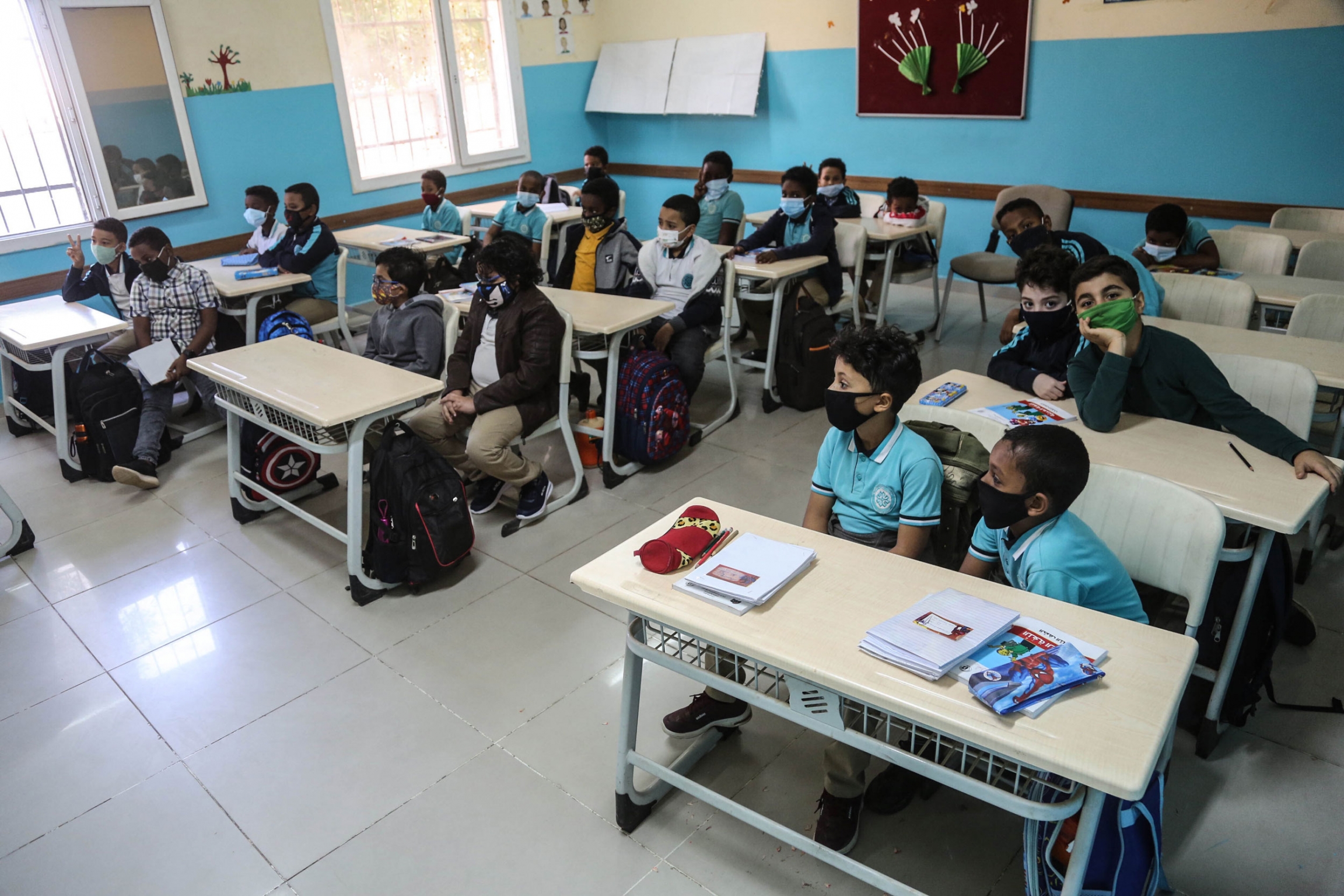 Students are seen at their classroom in Khartoum, Sudan, Feb. 01, 2021. Three rows of desks are shown with two students sitting at each desk in a classroom with blue and white walls.