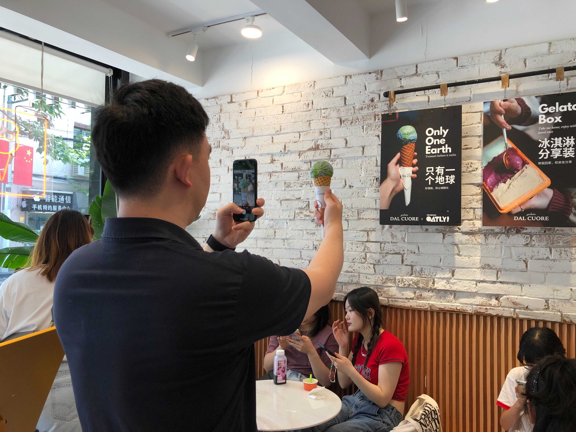 China experiments with ice cream flavors A man holds up a cone with blue and green ice cream as he takes a photo of it against a poster