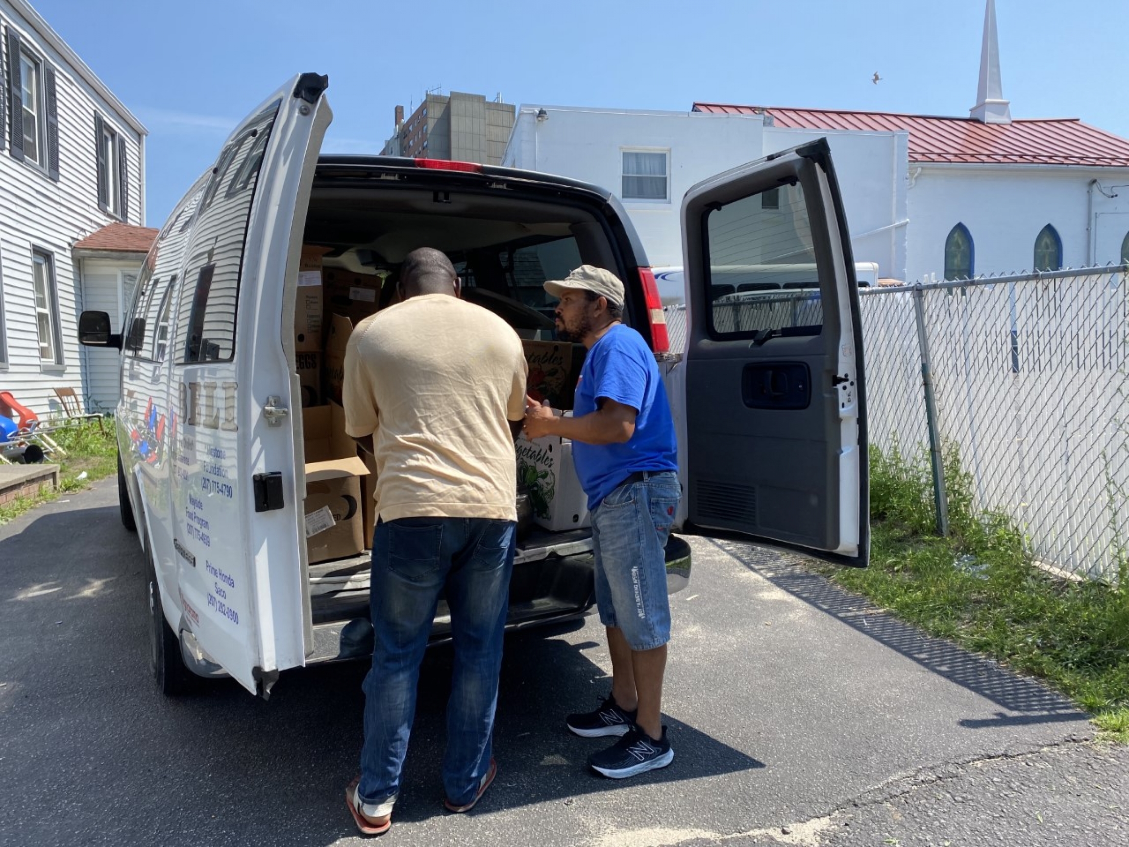 Rui Pires, right, speaks with a member of the Angolan community during his food delivery route in Portland, Maine Rui Pires, right, speaks with a member of the Angolan community during his food delivery route in Portland, Maine