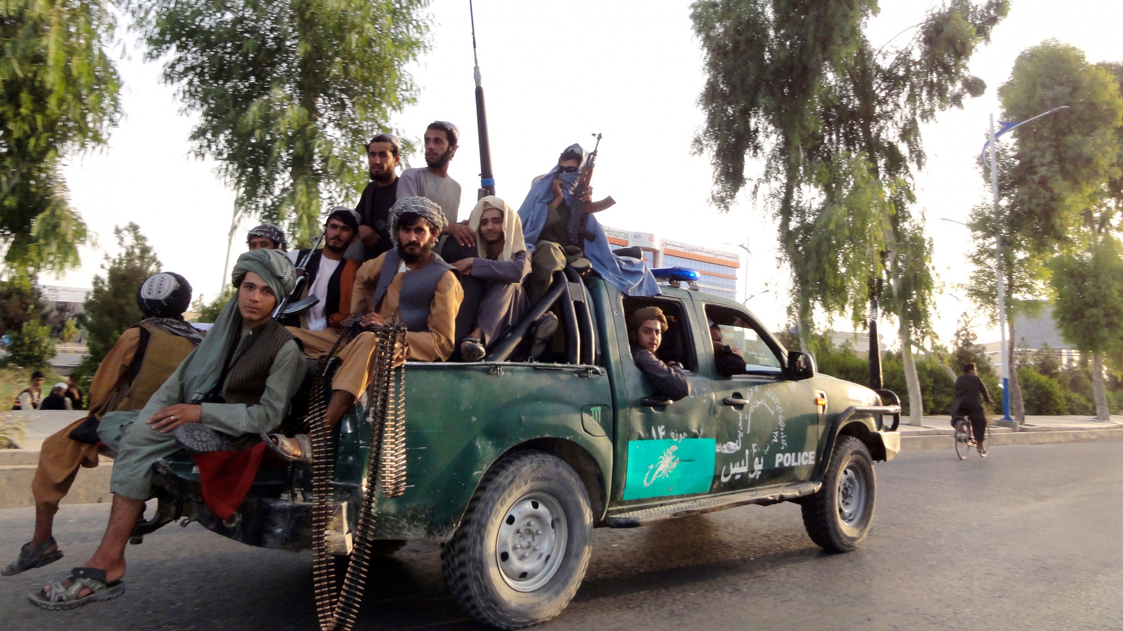 Taliban fighters patrol inside the city of Kandahar, southwest Afghanistan, Sunday, Aug. 15, 2021. Several Taliban fighters are shown sitting in the back of a pickup truck, several holding weapons.