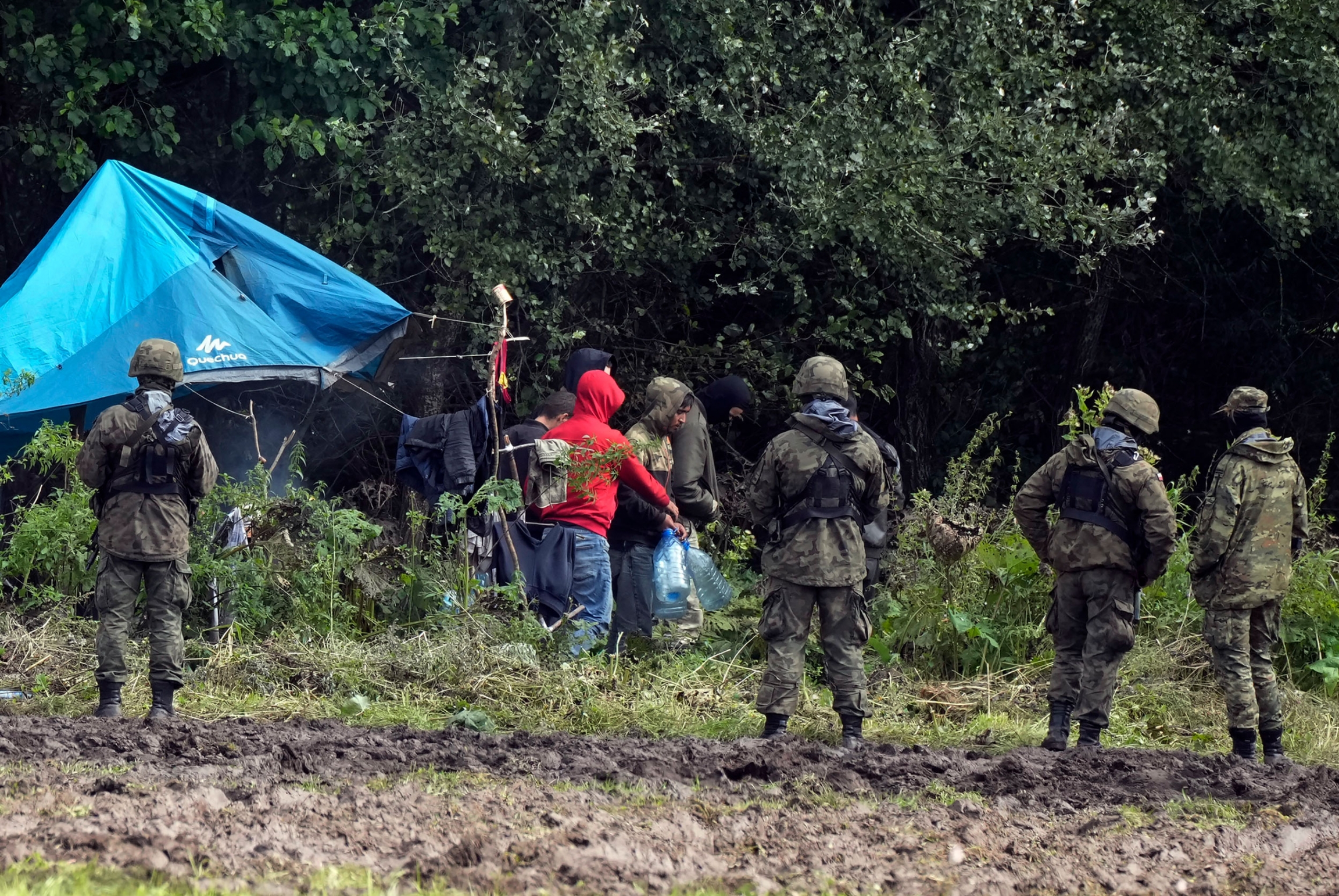 Migrants stuck along the Poland-Belarus border carry plastic water bottles as they are surrounded by Polish forces in Usnarz Gorny, Poland, on Wednesday, Sept. 1, 2021. Migrants stuck along the Poland-Belarus border carry plastic water bottles as they are surrounded by Polish forces in Usnarz Gorny, Poland, on Wednesday, Sept. 1, 2021.