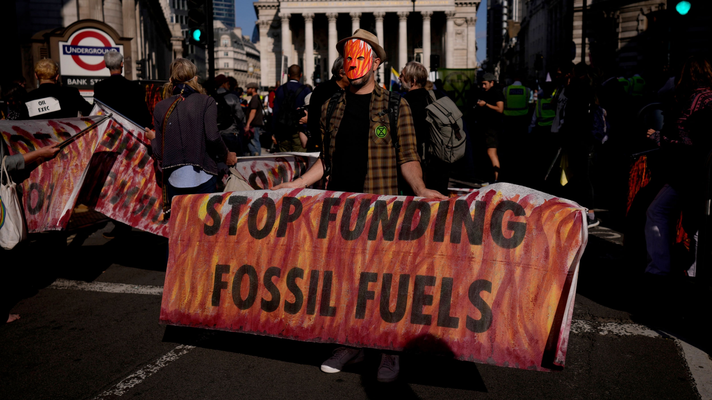 In this Thursday, Sept. 2, 2021 file photo, an Extinction Rebellion climate change activist holds a banner backdropped by the Bank of England, at left, and the Royal Exchange, center, in the City of London financial district in London. In this Thursday, Sept. 2, 2021 file photo, an Extinction Rebellion climate change activist holds a banner backdropped by the Bank of England, at left, and the Royal Exchange, center, in the City of London financial district in London.