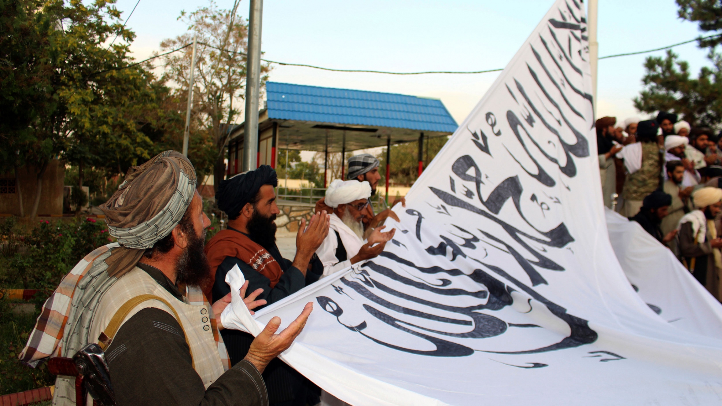 Taliban fighters pray while raising their flag at the Ghazni provincial governor's house, in Ghazni, southeastern, Afghanistan, Sunday, Aug. 15, 2021. Taliban fighters pray while raising their flag at the Ghazni provincial governor's house, in Ghazni, southeastern, Afghanistan, Sunday, Aug. 15, 2021.
