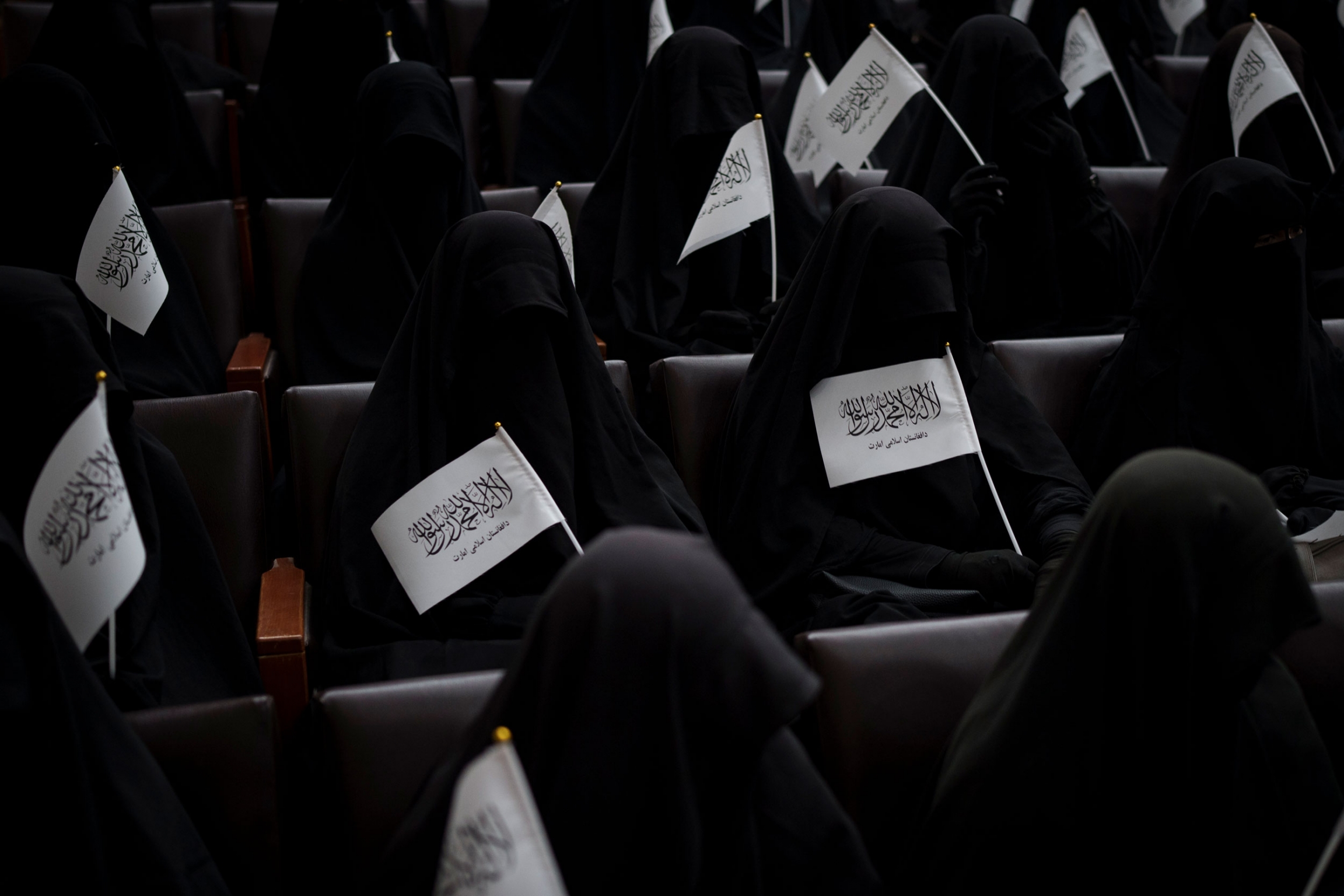 Women wave Taliban flags as they sit inside an auditorium at Kabul University's education center during a demonstration in support of the Taliban government in Kabul, Afghanistan, Saturday, Sept. 11, 2021.