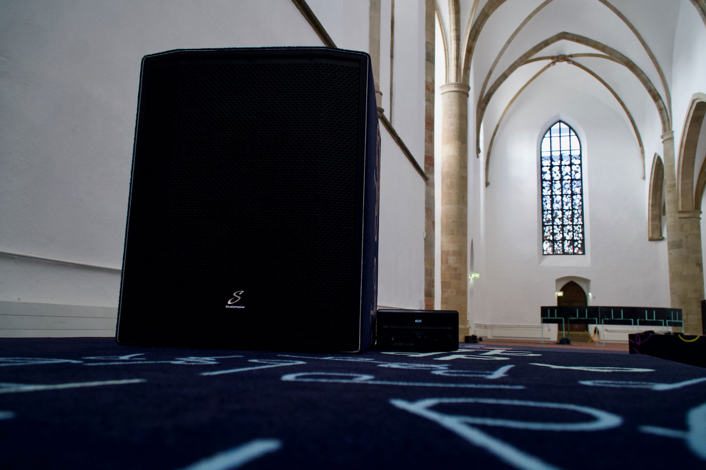 An up-close image of a speaker in Alison O'Daniel's art exhibit, "I Felt People Dancing." An up-close image of a speaker within a church with high ceilings.