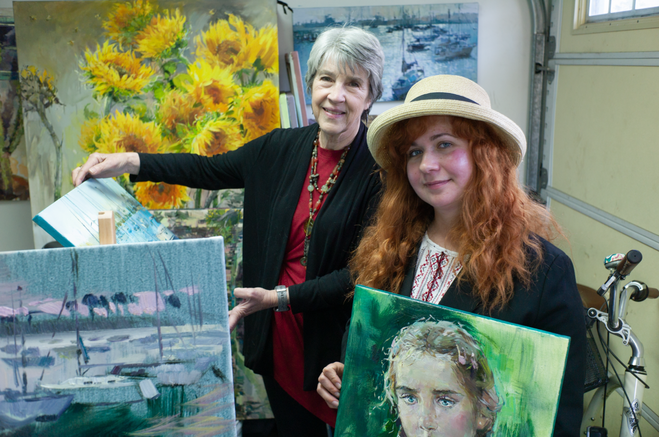 Ukrainian artist Vira Ustyanska with her host Connie Terwilliger in San Diego. At the garage-turned-art studio at Terwilliger's house, Ustyanska paints large canvases of sunflowers, her favorite subject.
