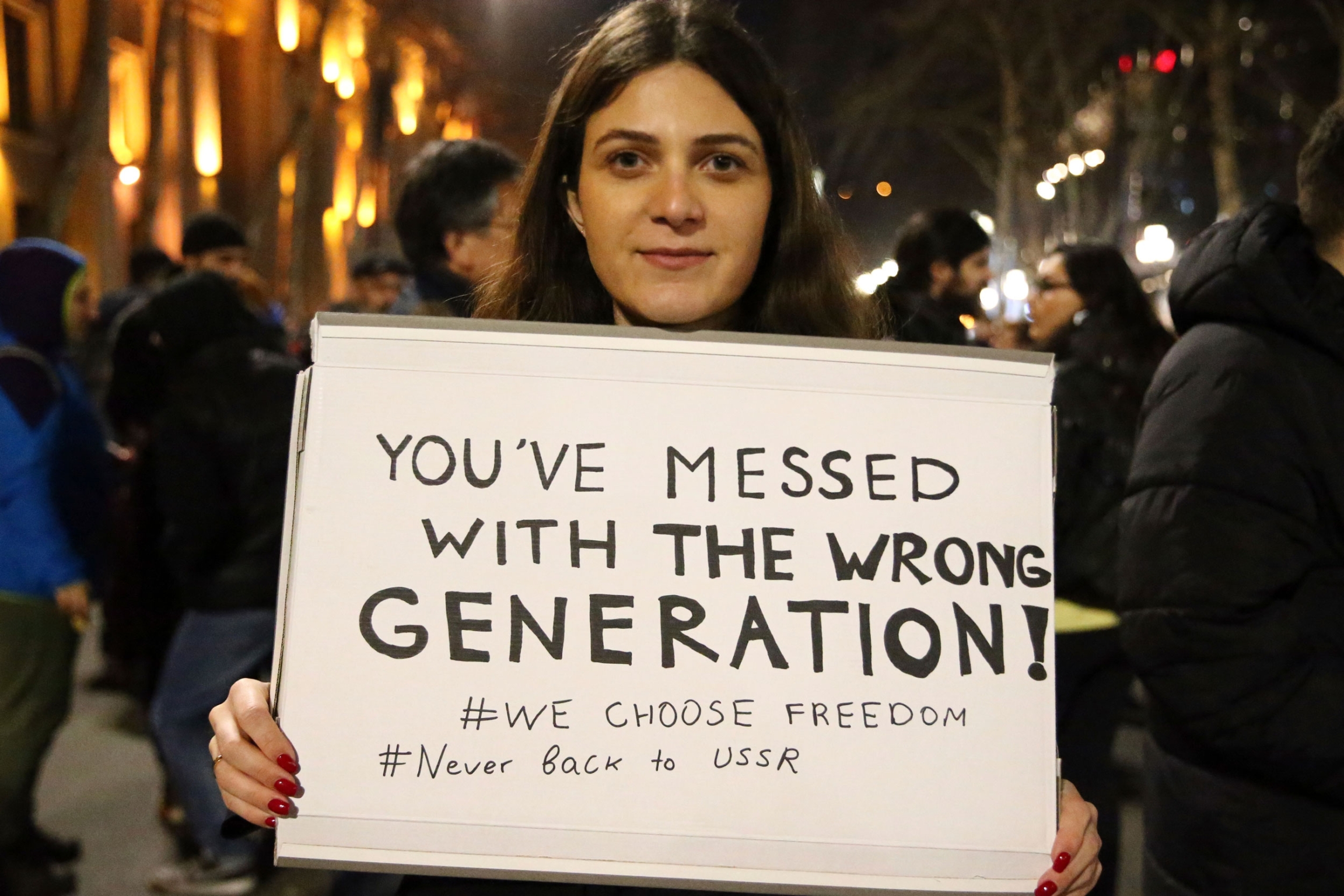 A woman holds a poster during a rally against a draft law aimed at curbing the influence of 