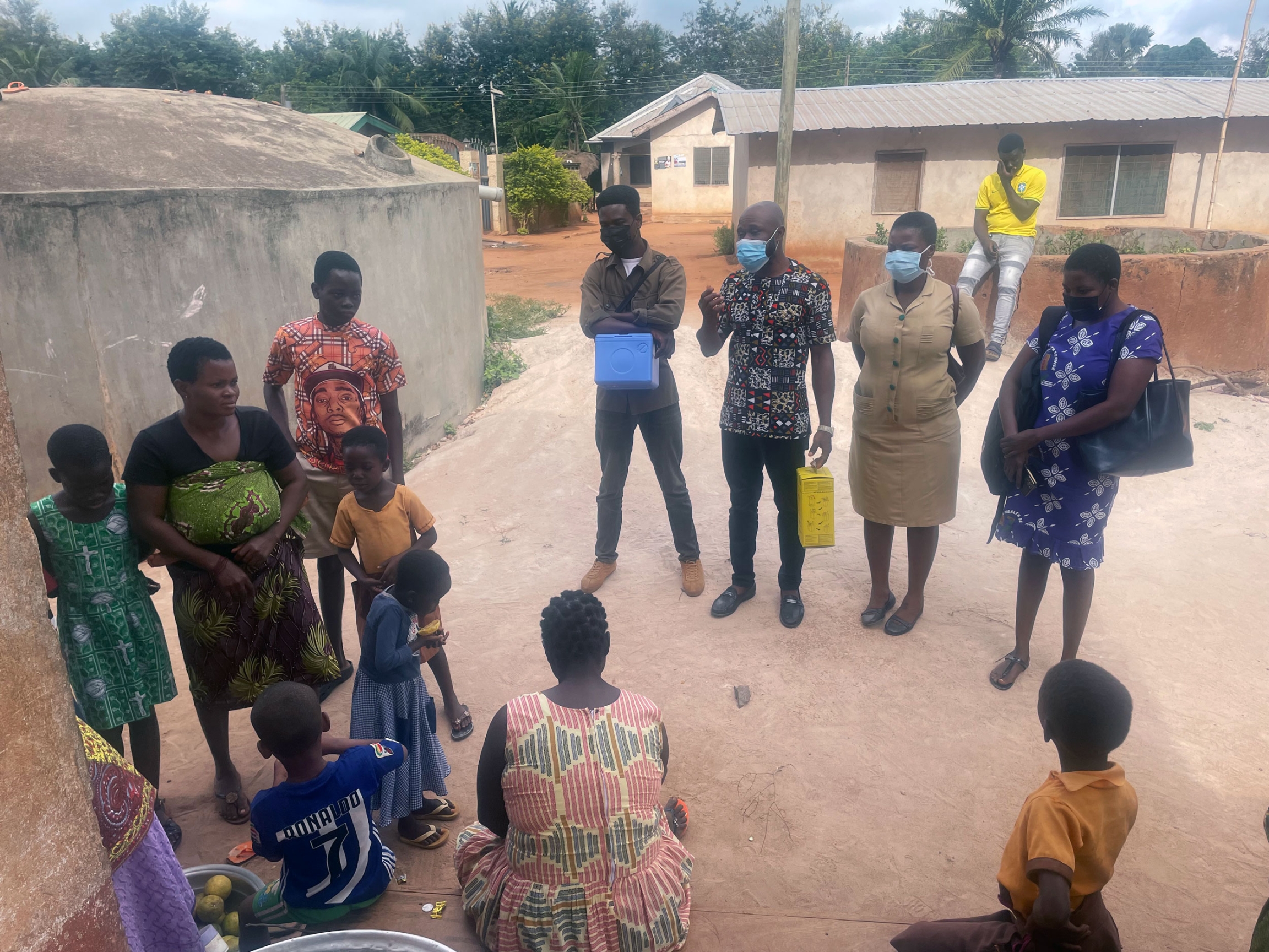 A group of health workers stand in a circle in a village during a vaccination drive. 