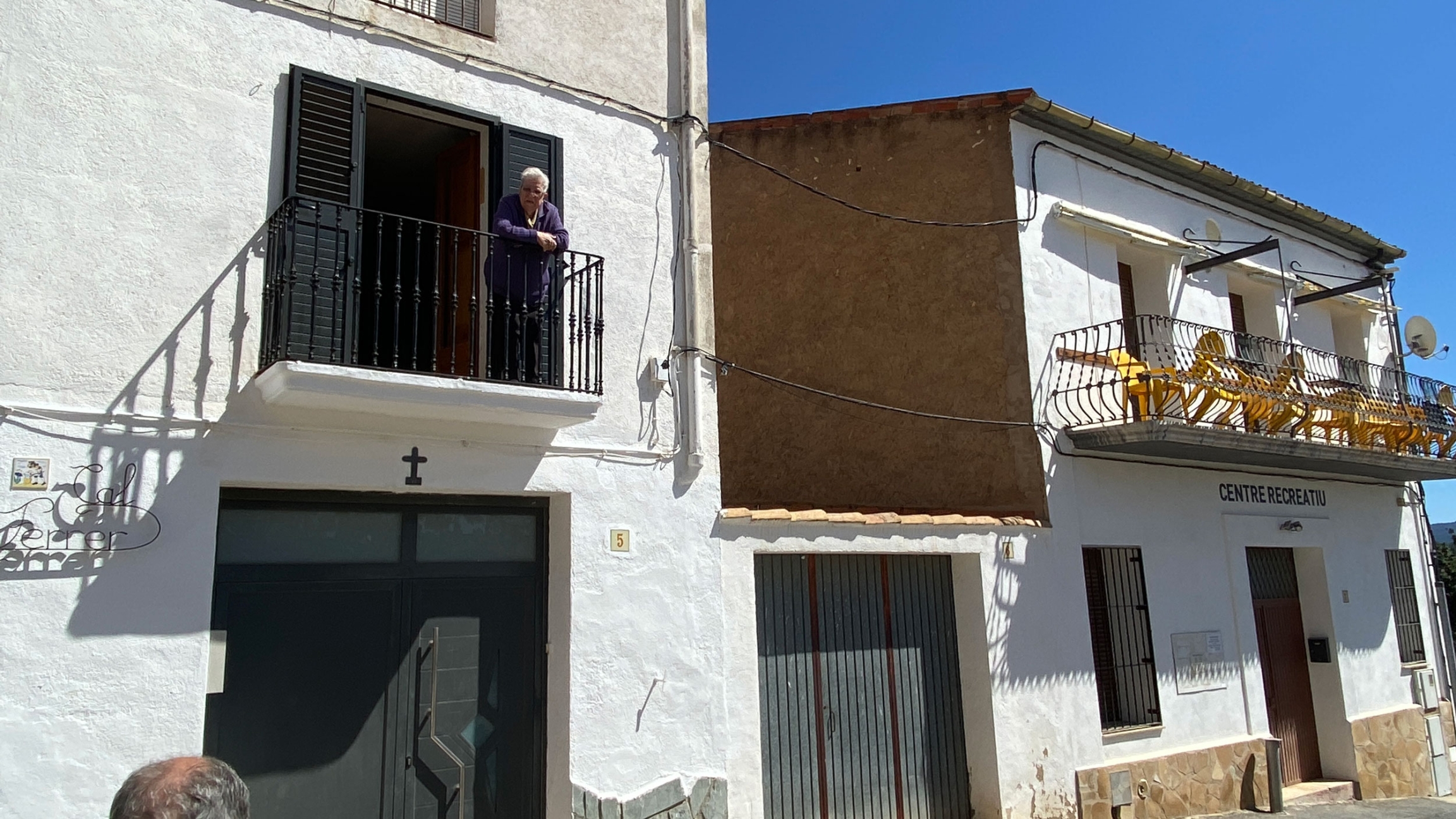 A woman on her balcony chats with a man on the street, next to the town’s bar which was closed that day. 
