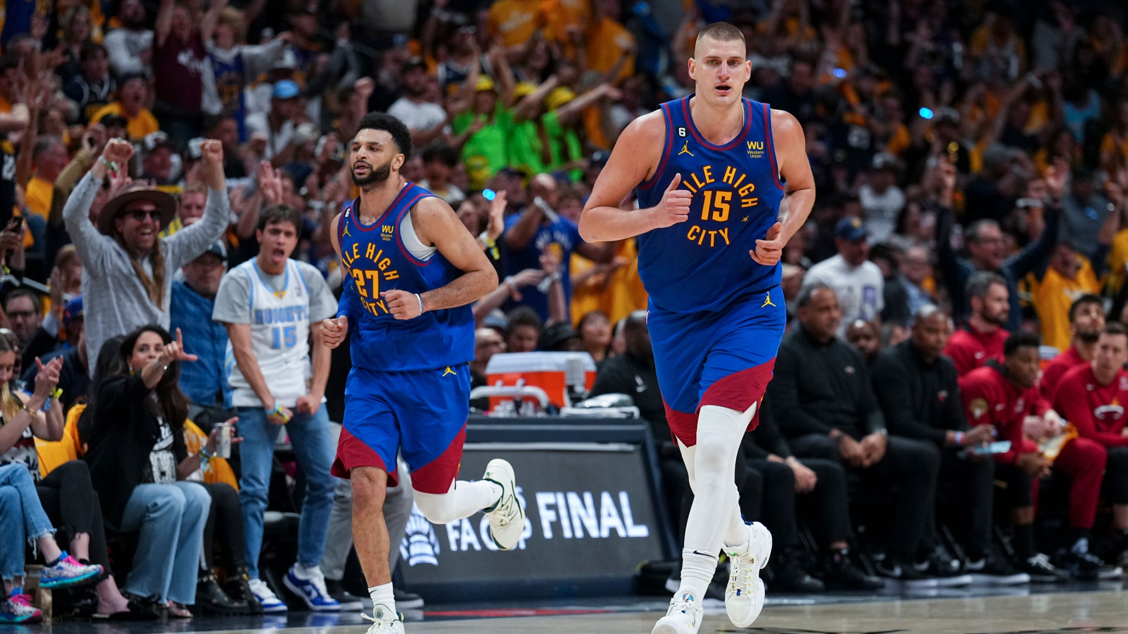 Denver Nuggets center Nikola Jokic, right, jogs on the court during the second half of Game 1 of basketball's NBA Finals against the Miami Heat, Thursday, June 1, 2023, in Denver.