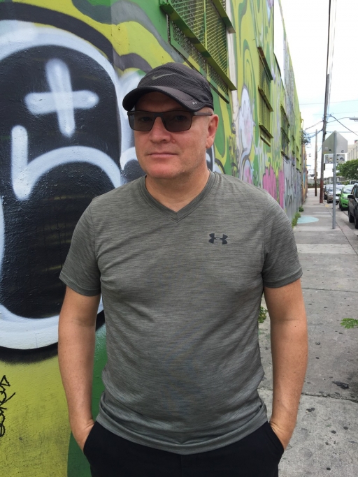 Man standing on sidewalk, wearing sunglasses