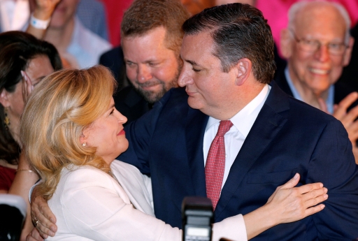 Man in suit embraced by woman, who holds onto his arm