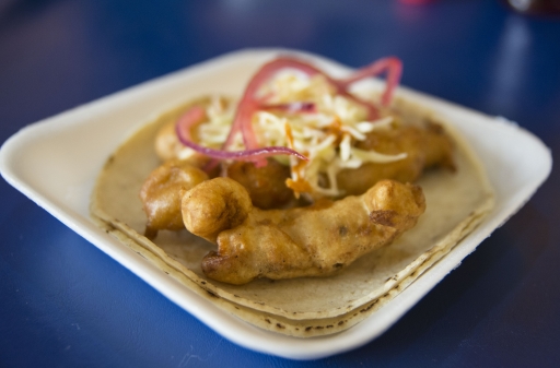 Pieces of fried fish on a tortilla on a white plate.