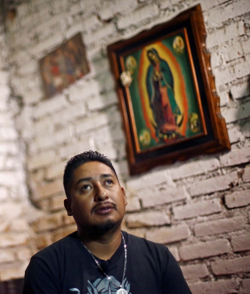 A man looks on with a painting of the Virgin Mary in the background