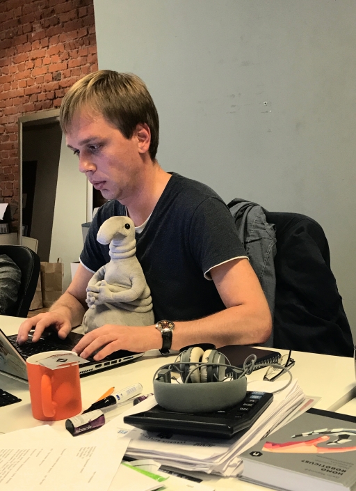 A man sits with a stuffed toy in front of him typing on a computer