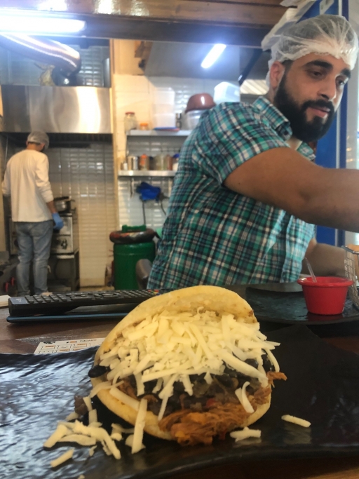 A close-up photo of Firas Yorgi making an arepa on a grill.