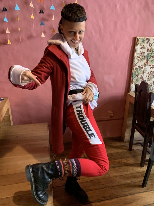 A woman gestures to her red leggings, where the word trouble is written.