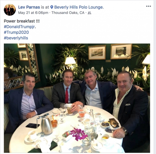 Men in suits sit around a table.