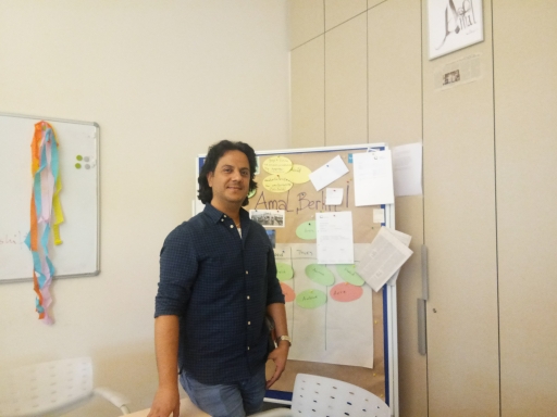 Syrian journalist Abdolrahman Omaren reports for Amal, Berlin! in Arabic. He used to work in Syria as a broadcast journalist and reported on the Assad regime in Dubai, before he arrived in Berlin, Germany. A man stands in a newsroom with a noticeboard behind him.