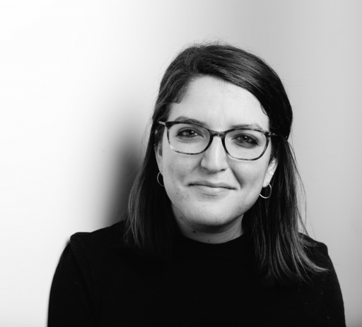Anna Kusmer A woman wearing a dark sweater and glasses looks at the camera.
