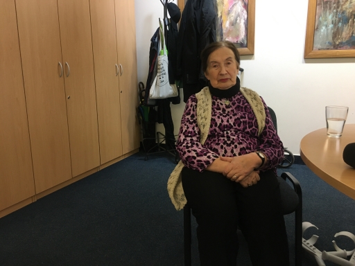 Zofia Radzikowska, 84, wears a purple shirt and sits with her hands crossed.