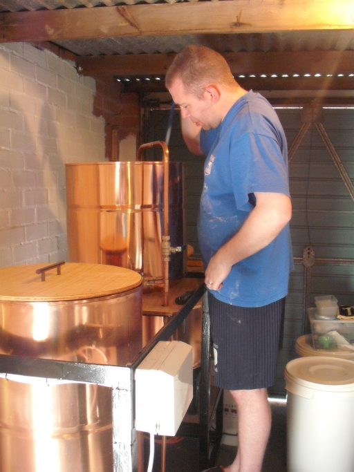 Richard Muir of Muir House Brewery stands over his brewer's kit in his garage. A man stands over a brewer's kit