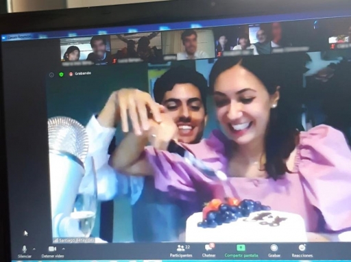 A man and woman smile and hold a cake with fruit on top.