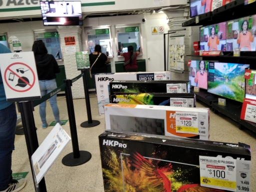 An electronics store and bank owned by billionaire Ricardo Salinas Pliego, owner of Mexico's second largest TV network, sells TVs with the option to buy with monthly installments. A line at a bank next to TVs for sale in the same space