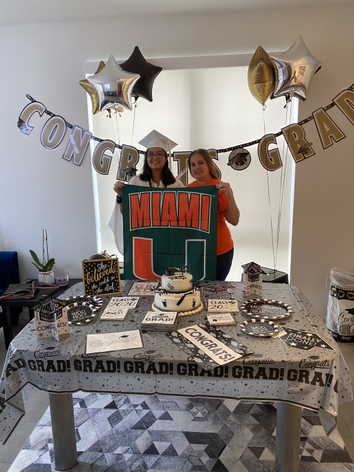Two people stand underneath a "congrats" sign with a Miami University banner